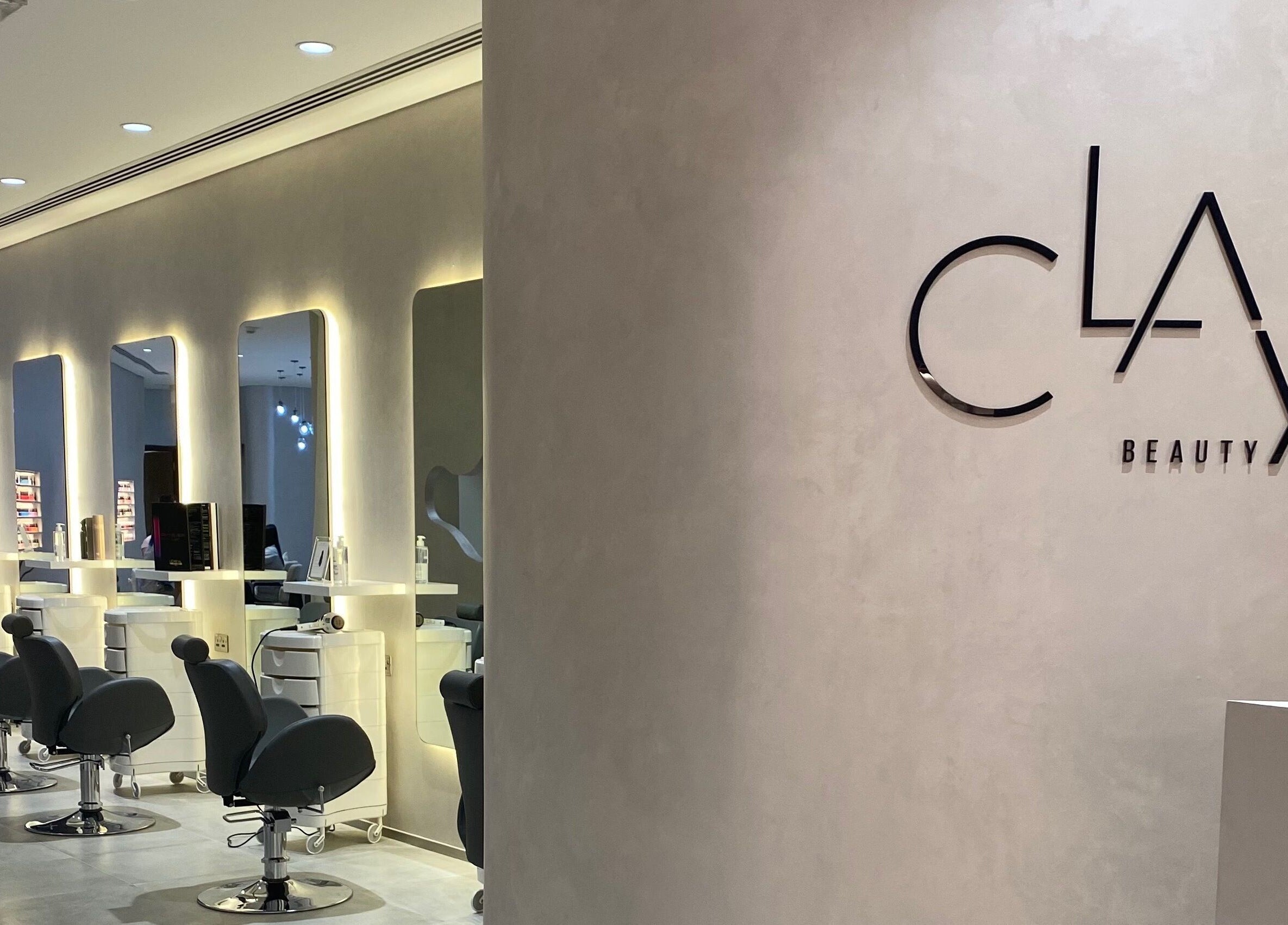 Chic interior of Clay Beauty Lounge - Khaldiya in Abu Dhabi, AE, featuring modern salon chairs and illuminated mirrors.