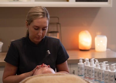 Therapist performing facial treatment at Chelle's Beauty, Lytham St Anne’s, England, GB. Candles and skincare products.
