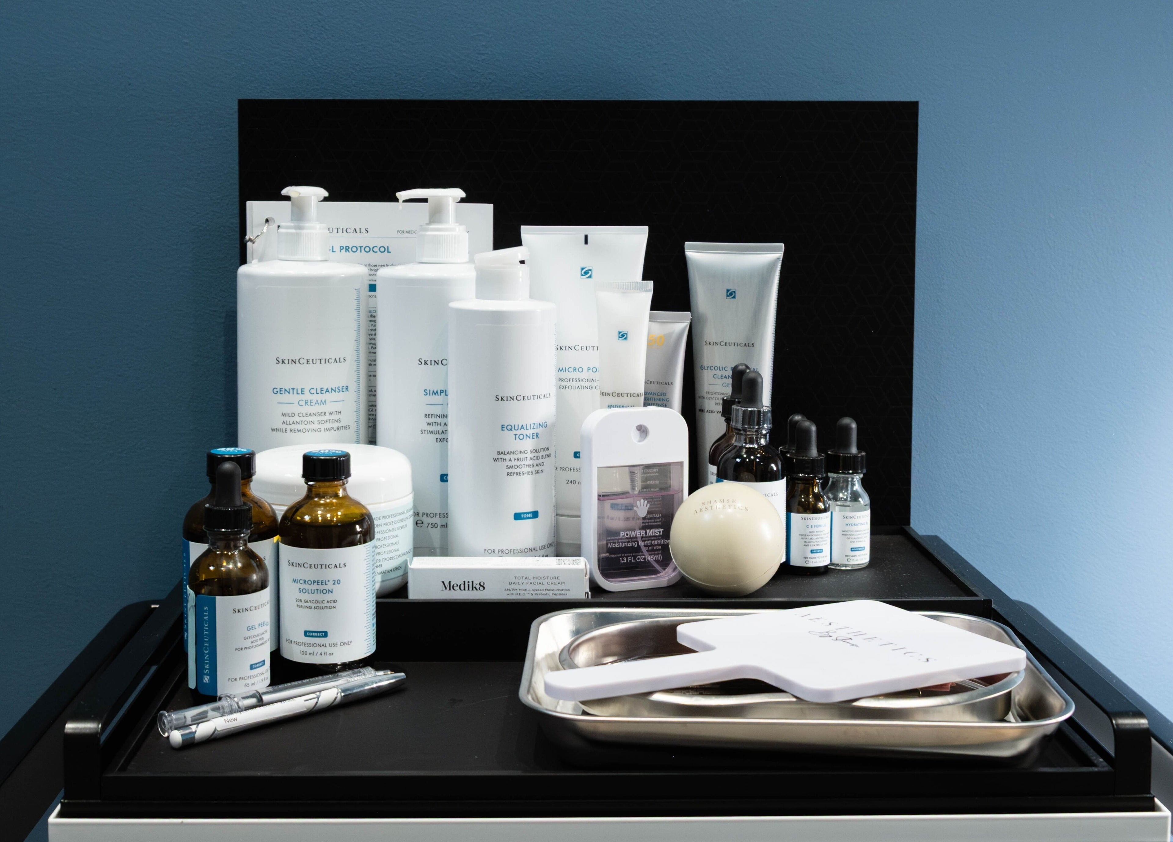 Premium skincare products at ShamseAesthetics Harley Street, London, England, GB, on sleek black shelf.