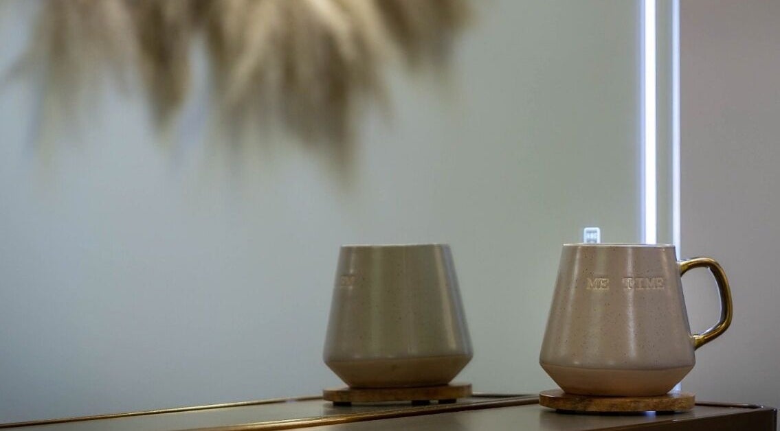 Elegant ceramic mug with 'ME TIME' text on a reflective surface at Utopia Hair Co, Clifton, England, GB.
