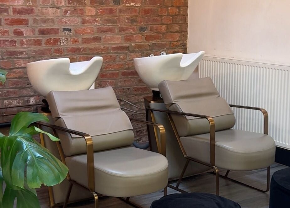 Modern wash stations at Utopia Hair Co in Clifton, England, GB, featuring sleek chairs and a brick wall.