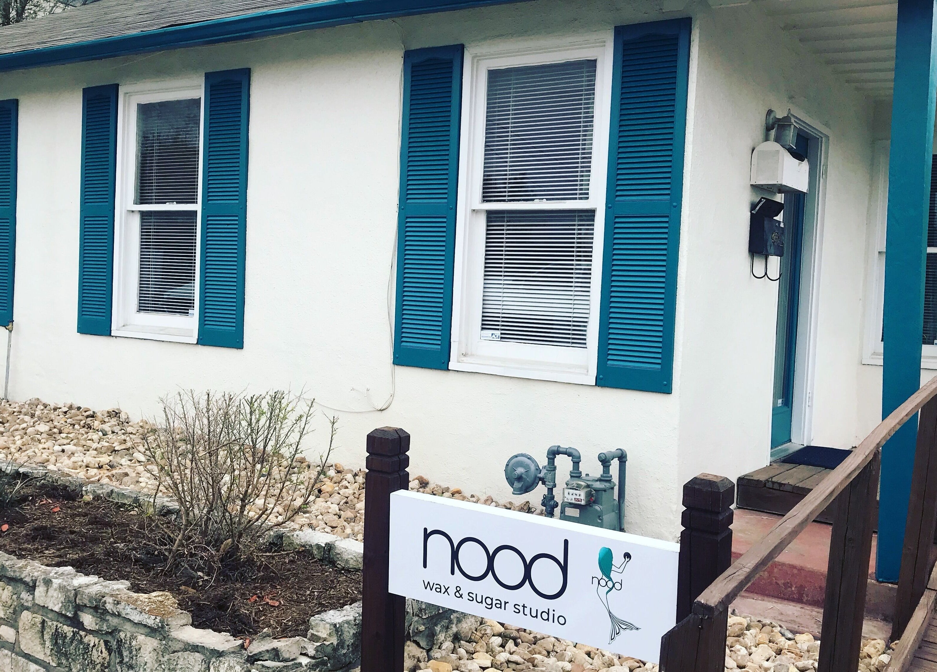 Exterior of Nood Wax & Sugar ATX studio in Austin, Texas, US with blue shutters and welcoming entry.