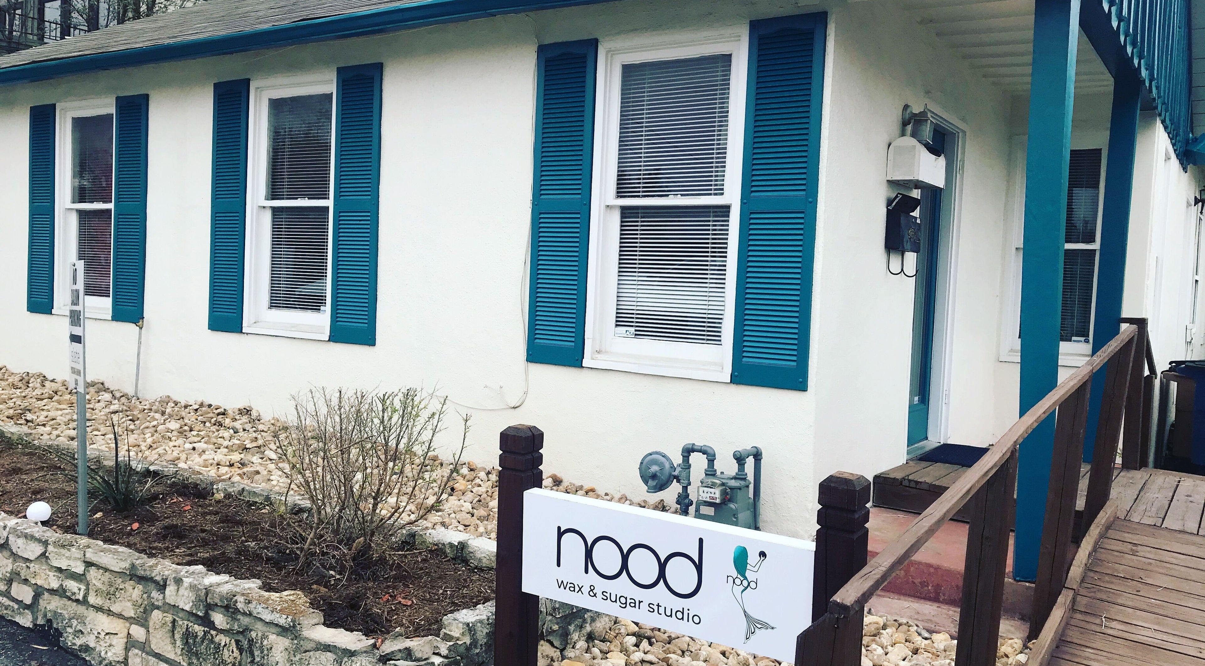 Exterior of Nood Wax & Sugar ATX studio in Austin, Texas, US with blue shutters and welcoming entry.