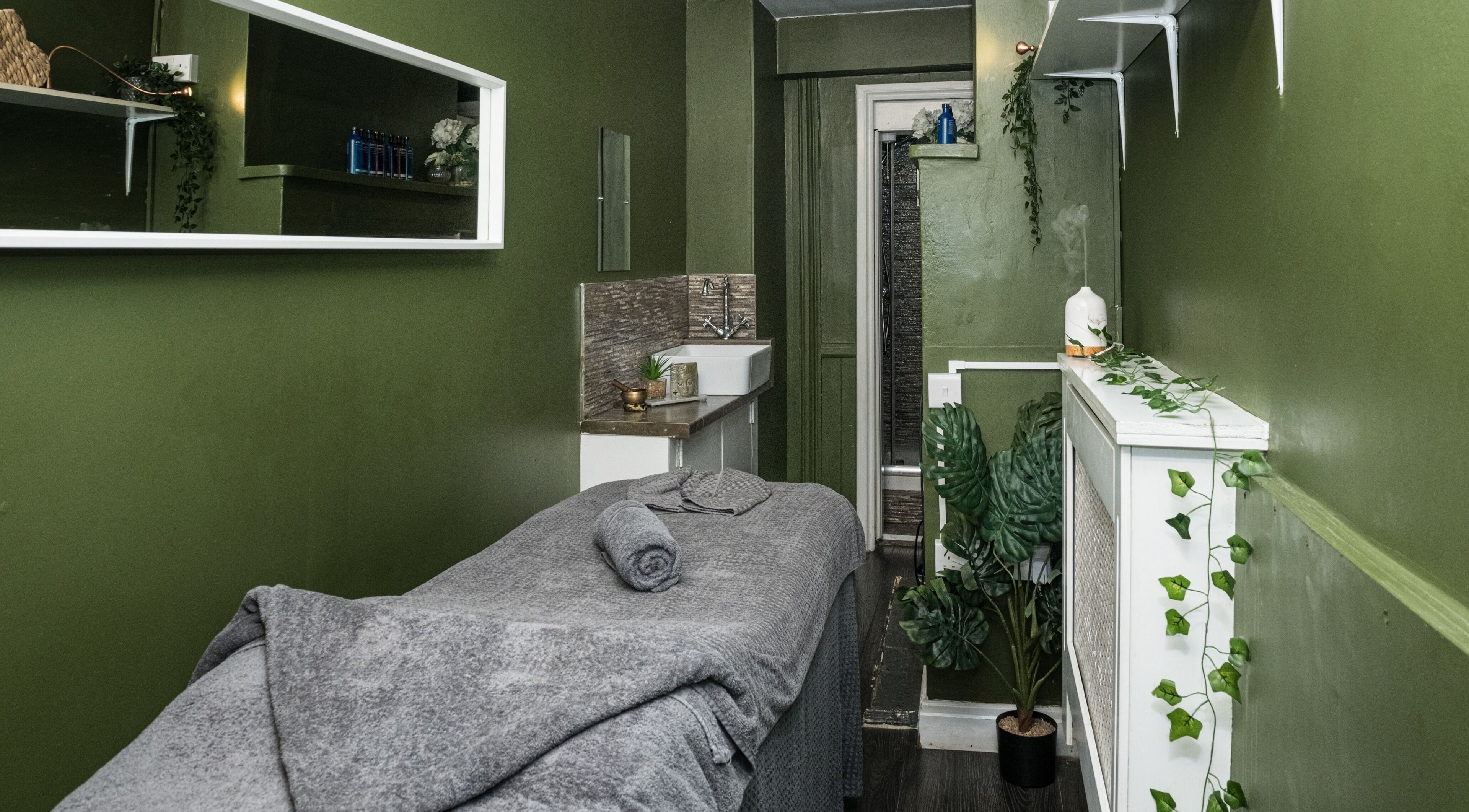 Tranquil massage room at Volta's Spa and Beauty in Twickenham, England, GB with green walls and ambient decor.