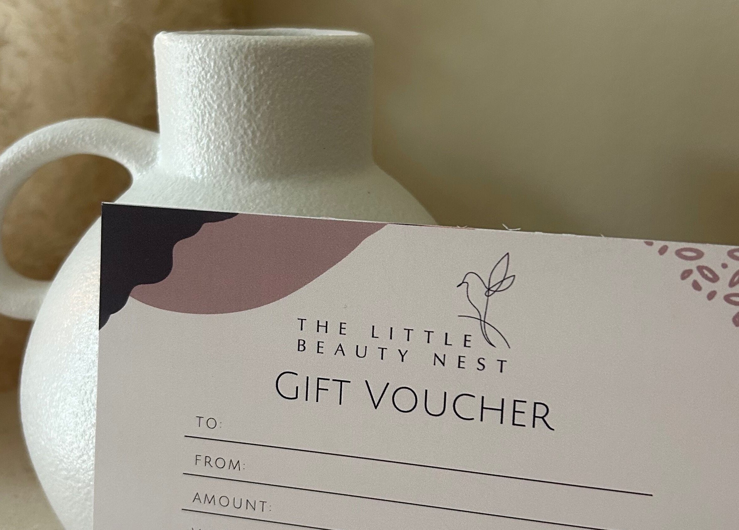 Gift voucher for The Little Beauty Nest, Ilkeston, England, GB beautifully presented beside a white ceramic vase.