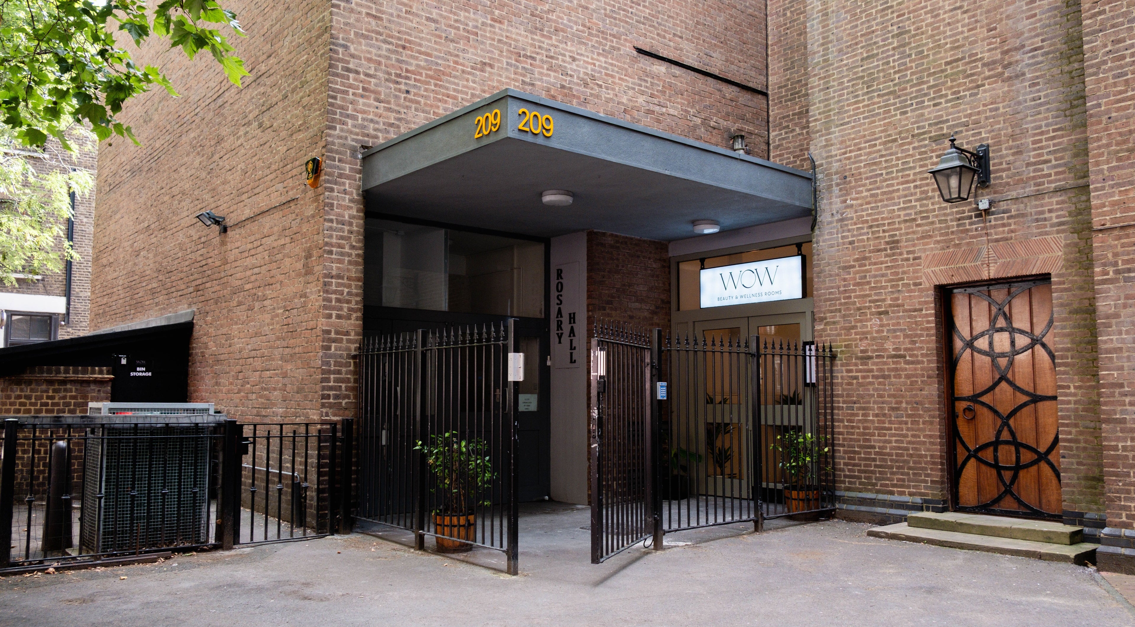 Entrance to O!GLOW-ON: byAudrey.ldn in London, England, GB framed by brick walls and a welcoming gate.