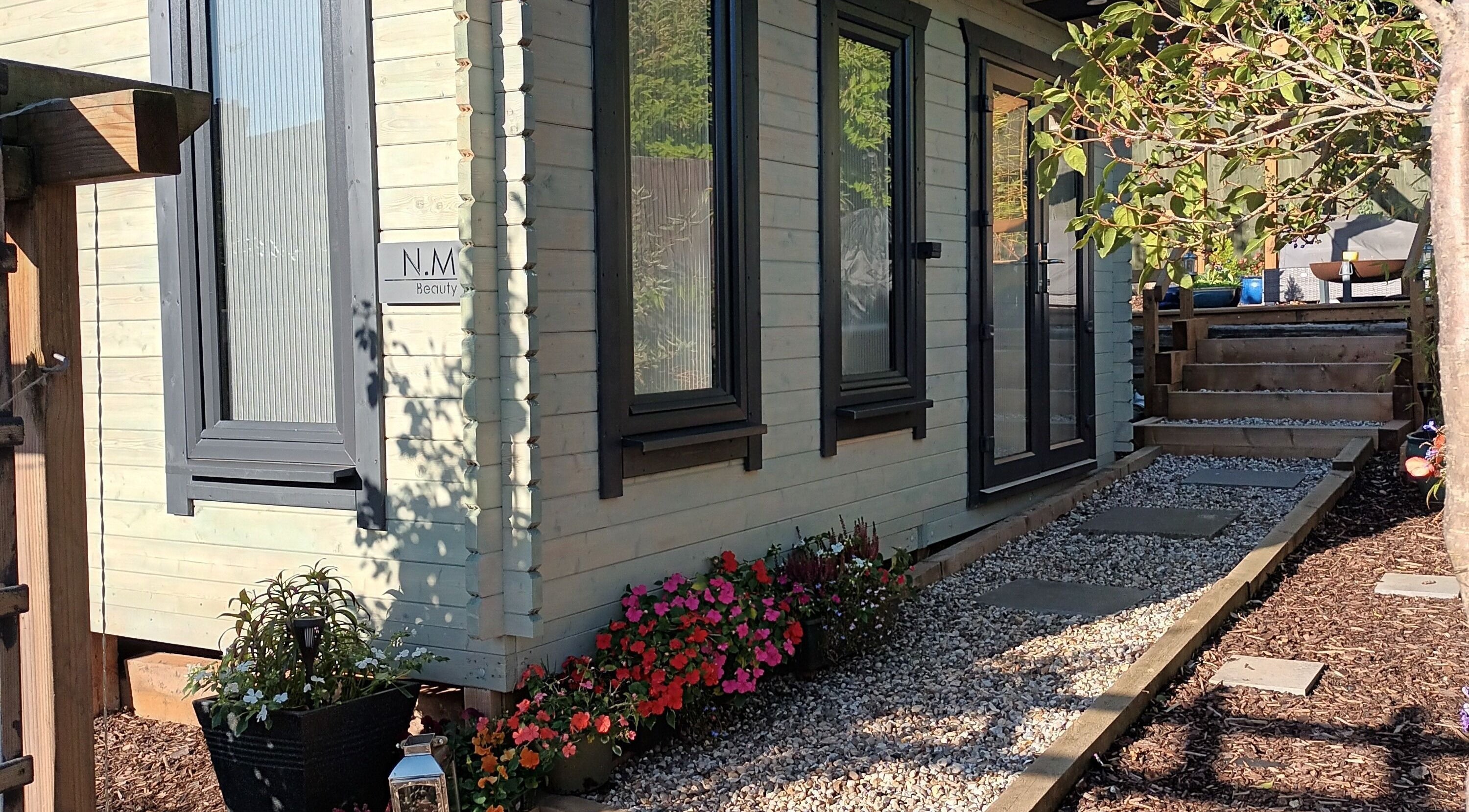 N.M Beauty venue entrance in Redditch, England, GB, with lush gardens and a serene pathway.
