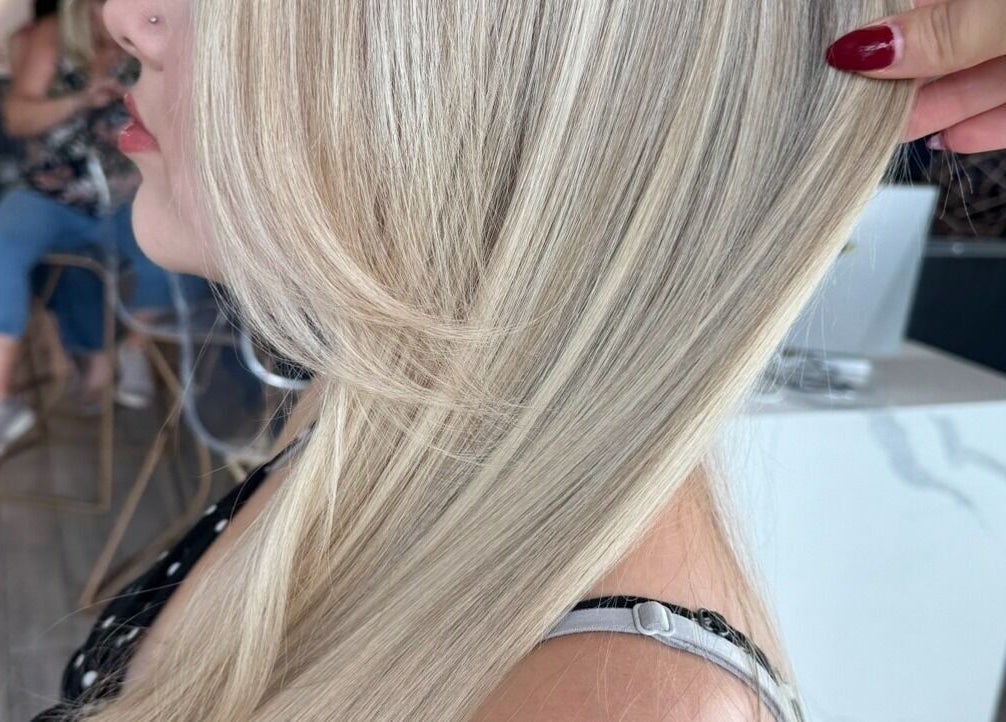 Blonde hair styled elegantly at Tipsy Salonbar Naples, Naples, Florida, US. Modern salon interior in the background.