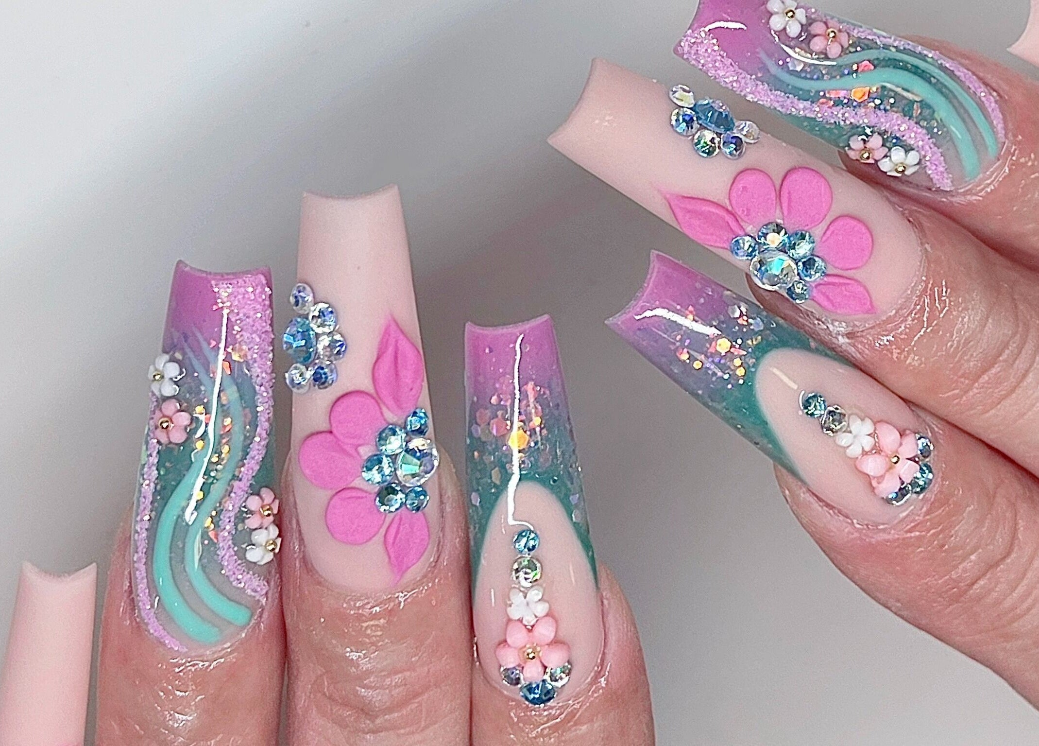 Detailed floral nail art at Tipsy Salonbar Naples, Naples, Florida, US, featuring pink and turquoise designs.