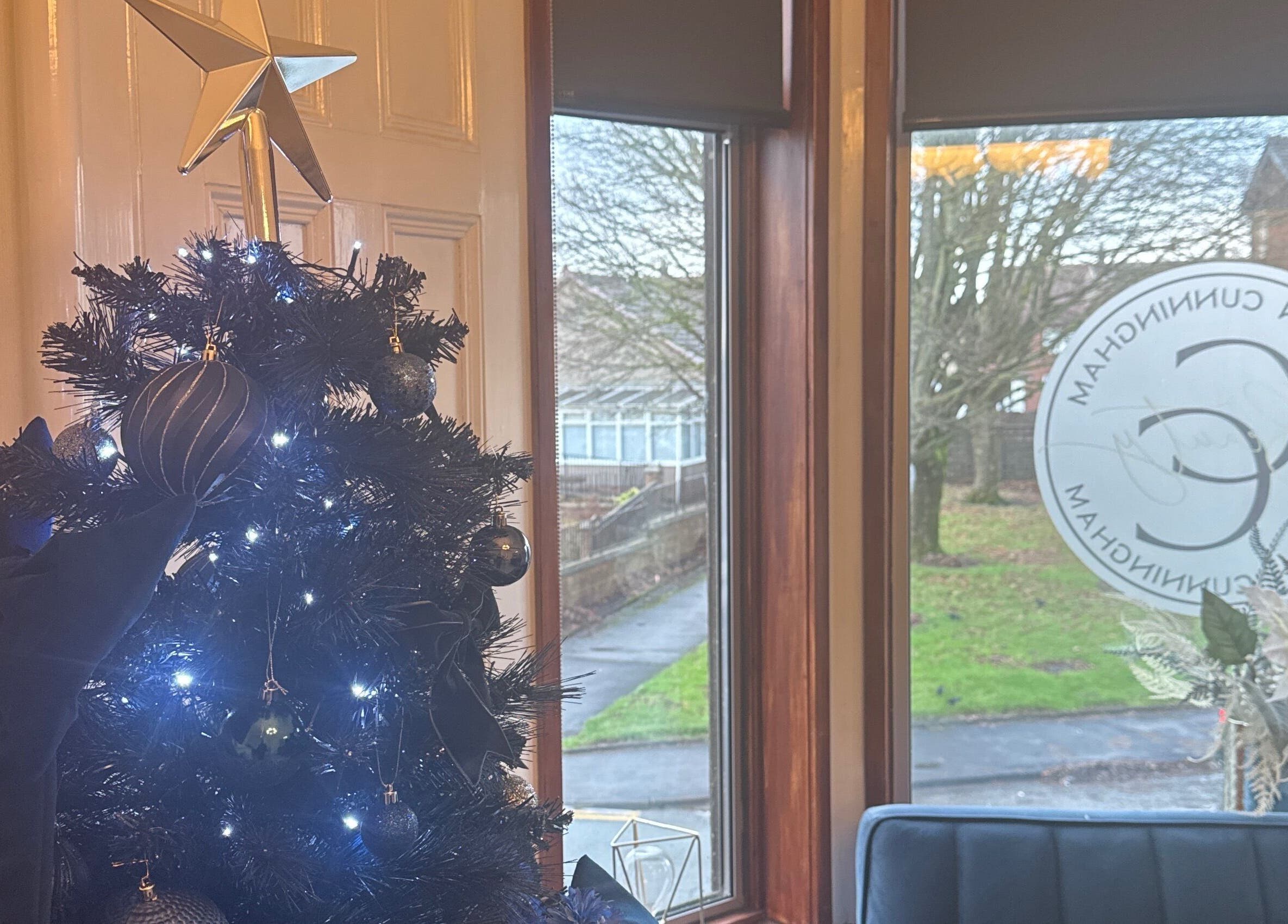 Festive decor at CCB Studios, Stenhousemuir, Scotland, GB with a lit Christmas tree by the window.