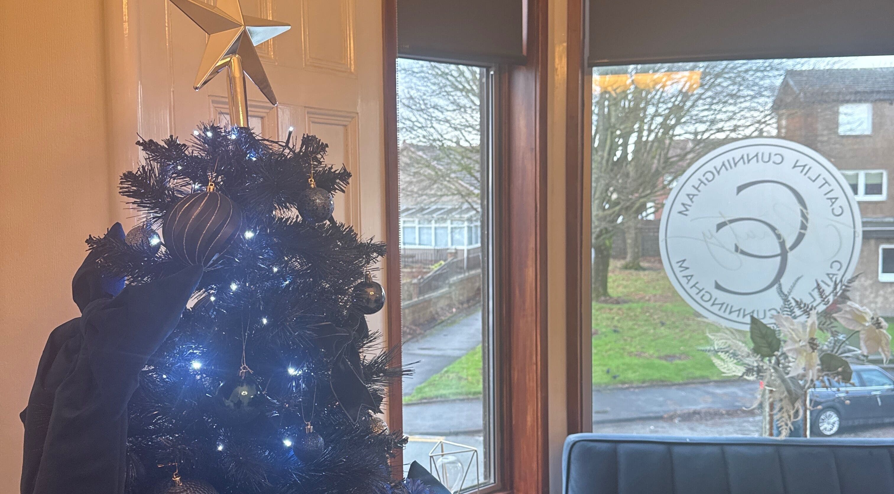 Festive decor at CCB Studios, Stenhousemuir, Scotland, GB with a lit Christmas tree by the window.