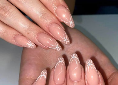 Intricate nail art design at AN Beauty, Alberton, Gauteng, ZA, showcasing delicate white patterns on nude nails.