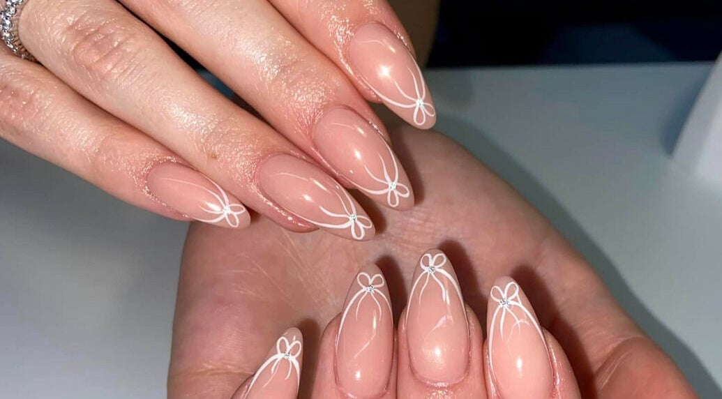Intricate nail art design at AN Beauty, Alberton, Gauteng, ZA, showcasing delicate white patterns on nude nails.