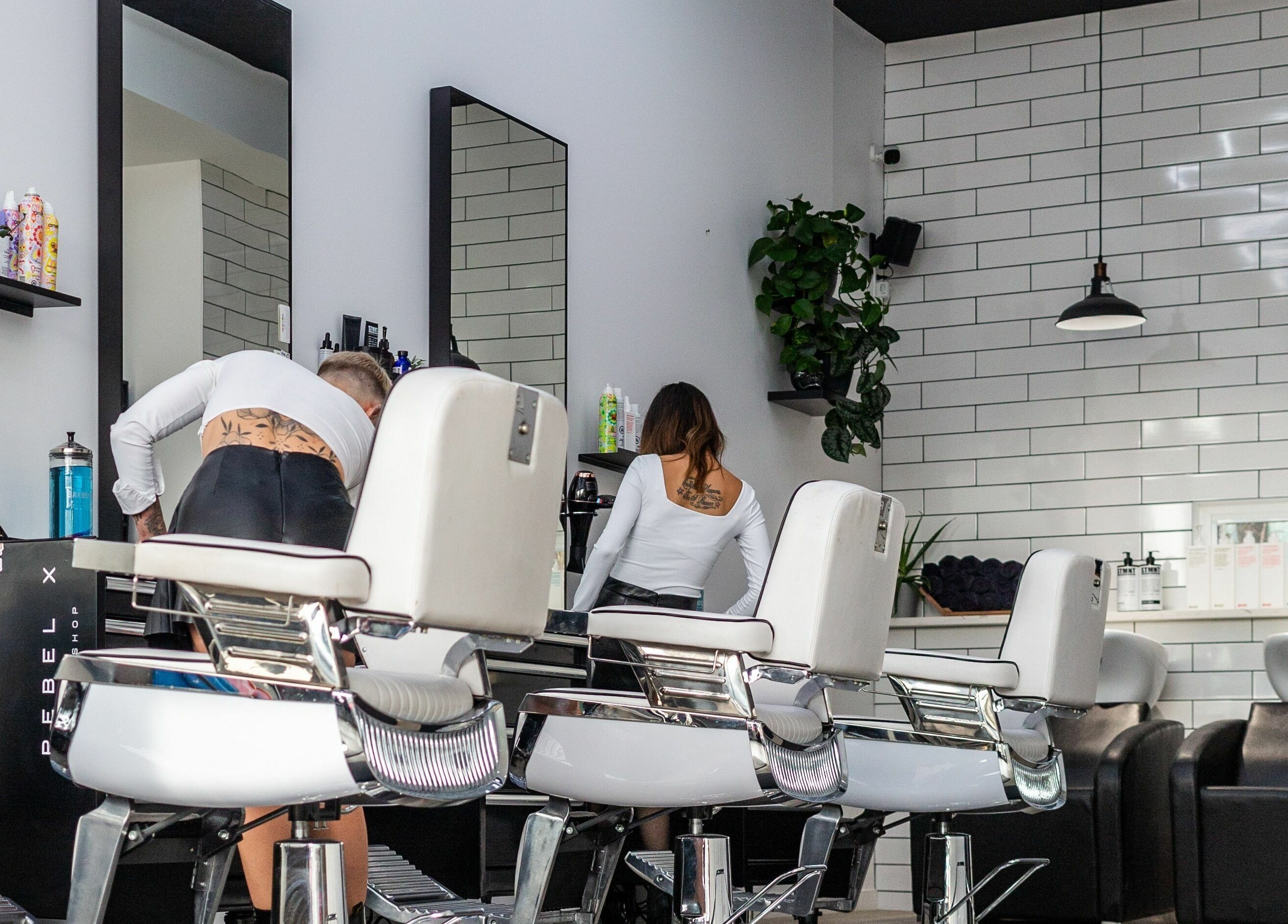 Modern salon interior at Rebel X, Calgary, Alberta, CA, featuring chic styling chairs and white tiled walls.