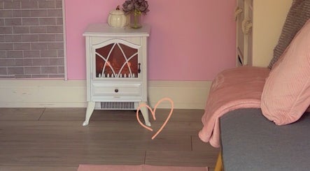 Charming pink corner at Kayotic Nails, Andover, England, GB with a decorative heater and soft seating.