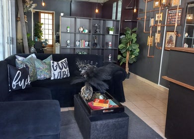 Cozy lounge at Dare to Ink Tattoo Studio, Bloemfontein, Free State, ZA. Black sofa with decor accents.