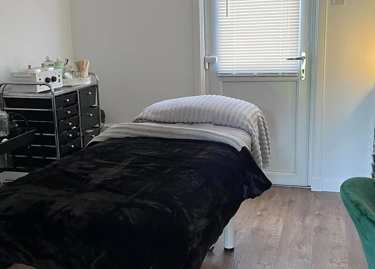 Relaxing therapy room at Beautywell, Addiewell, Scotland, GB with cozy bed and warm lighting.