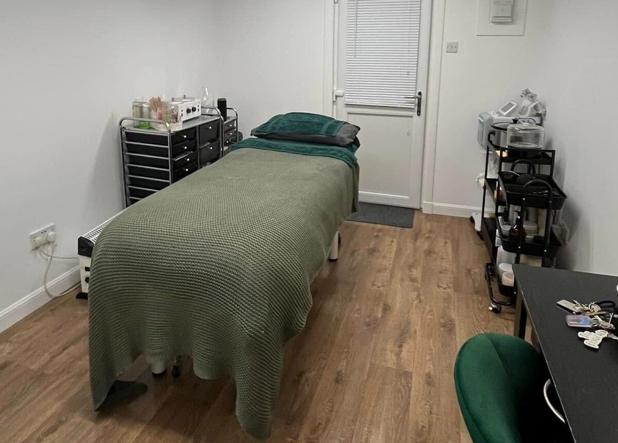 Calm treatment room at Beautywell in Addiewell, Scotland featuring a bed and soothing decor.
