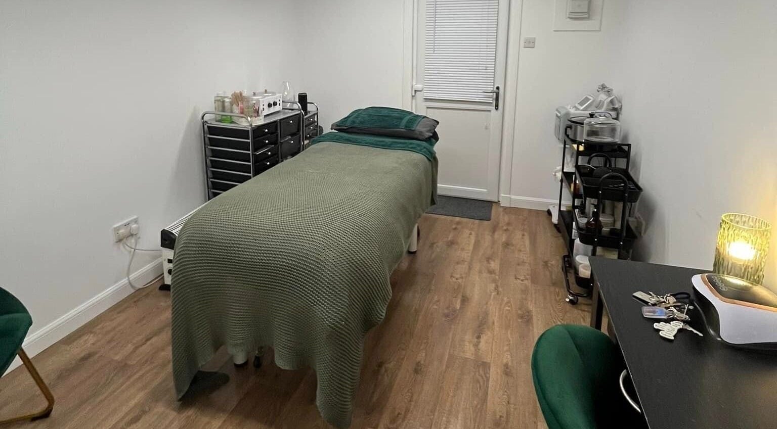 Calm treatment room at Beautywell in Addiewell, Scotland featuring a bed and soothing decor.