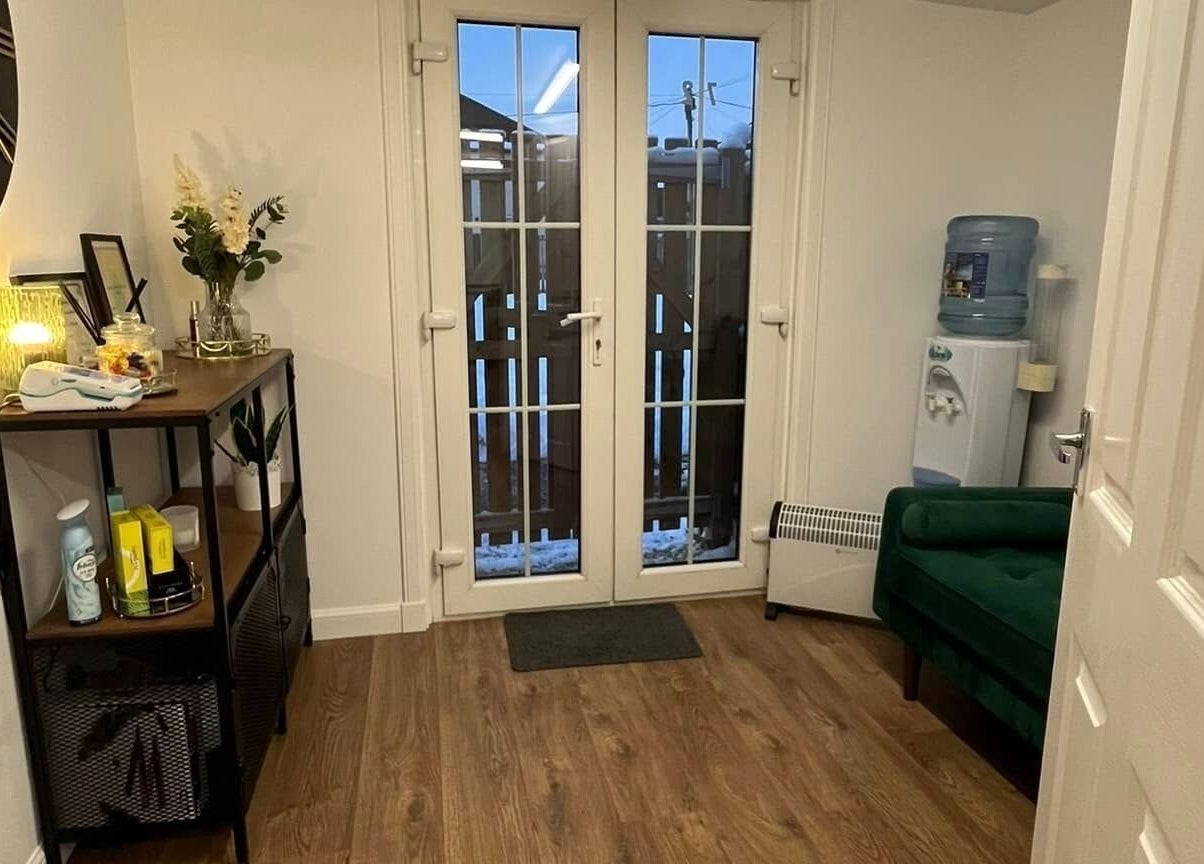 Cozy interior of Beautywell, Addiewell. Features elegant decor with a sofa and water cooler.