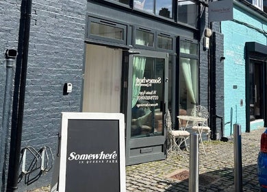 Front view of Somewhere in Queens Park venue, featuring brick walls and outdoor seating in London, England, GB.