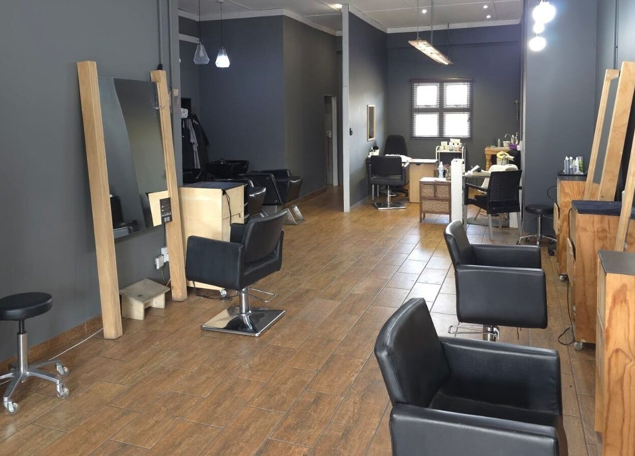 Modern salon interior at Manetain, Pretoria, Gauteng, ZA with sleek black chairs and wooden accents.