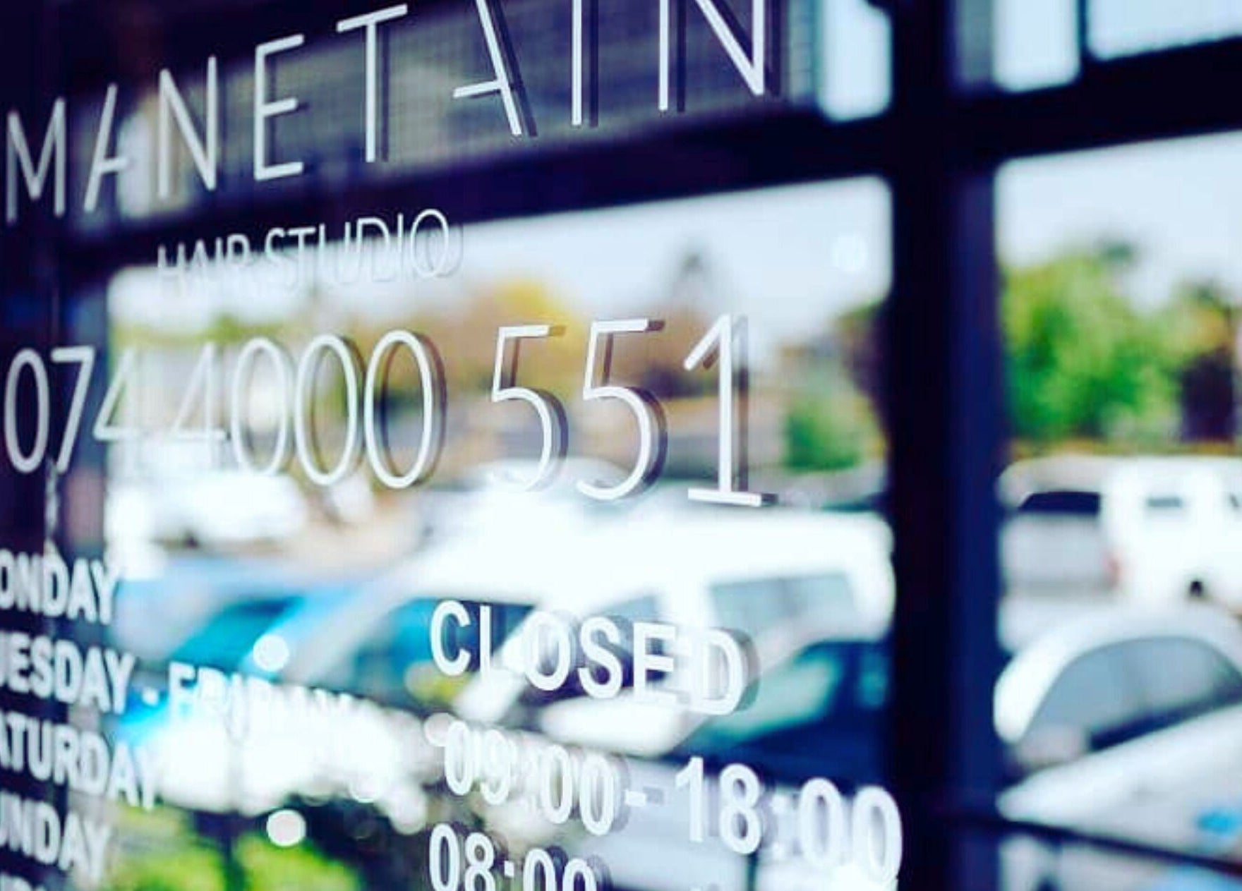 Reflection of Manetain's entrance door showing business hours in Pretoria, Gauteng, ZA.