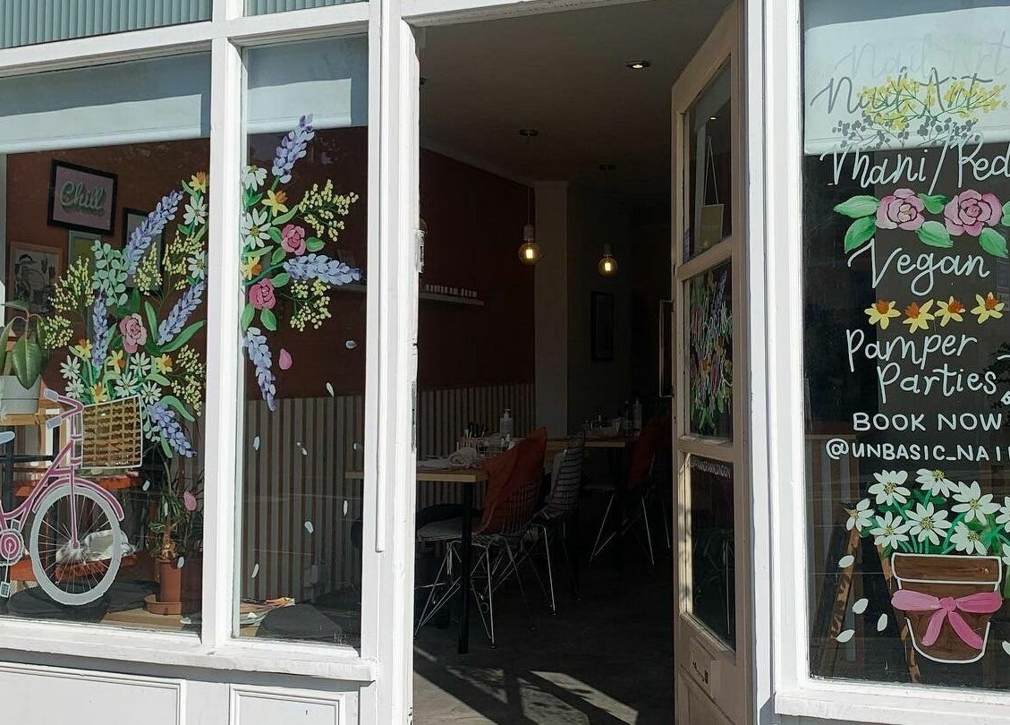Front window with colorful floral art and decor at Un|Basic, London, England, GB. Venue for beauty and pamper parties.