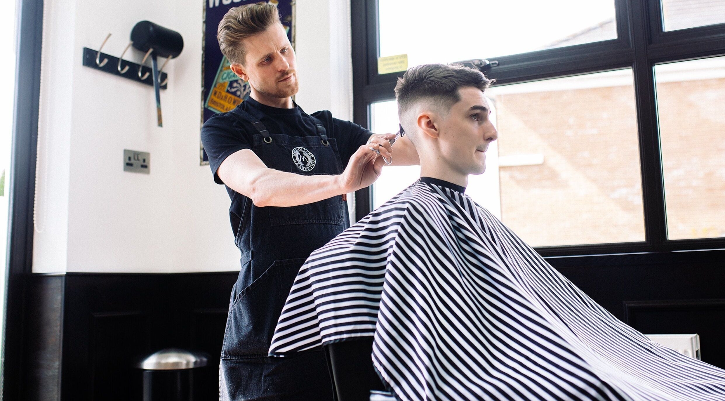 John at Mulholland Barbering in Portadown, Northern Ireland, GB expertly stylizes a client's hair.