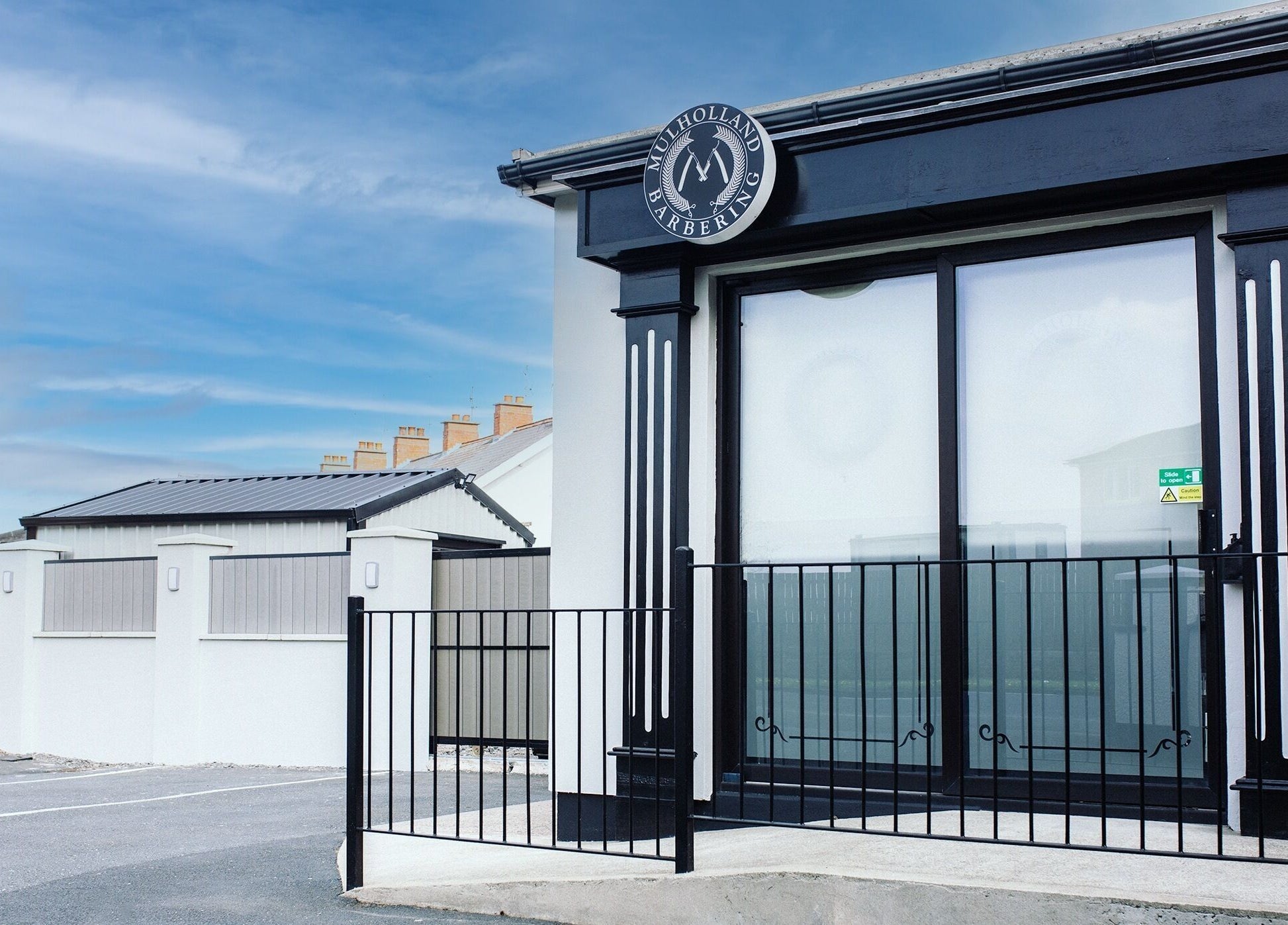 Exterior view of John at Mulholland Barbering in Portadown, Northern Ireland, GB with stylish black signage.