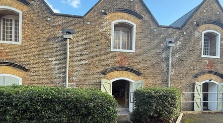 Charming brick exterior of No Bad Days, Rochester, England, GB, with green doors and hedges.