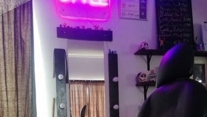 Interior de Yisus Style Barberia en Monterrey, Nuevo León, MX con silla y espejo iluminado por luz neón.