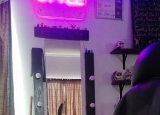 Interior de Yisus Style Barberia en Monterrey, Nuevo León, MX con silla y espejo iluminado por luz neón.