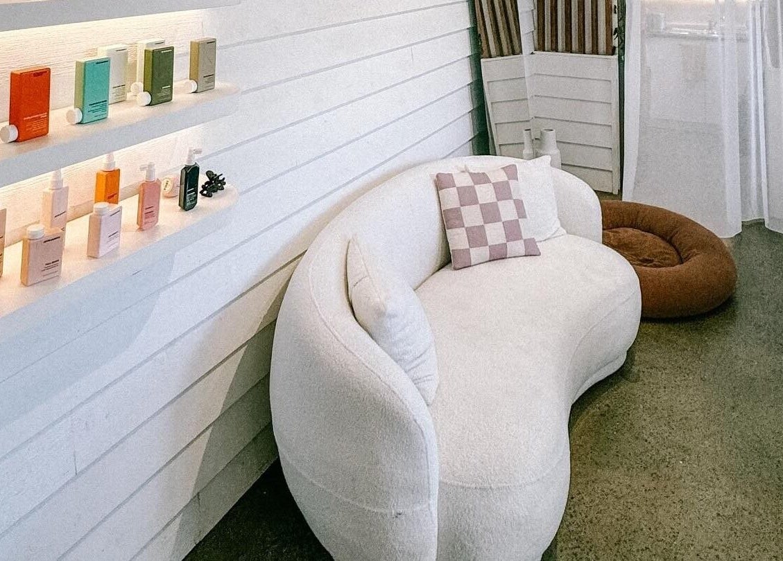 Chic lounge area at Rinsd Hair, Palm Beach, Queensland featuring plush sofa and displayed hair products.