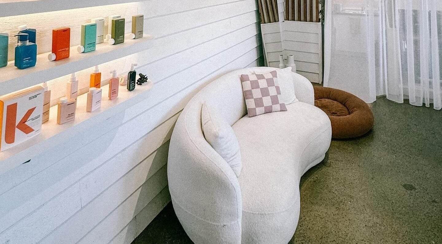 Chic lounge area at Rinsd Hair, Palm Beach, Queensland featuring plush sofa and displayed hair products.