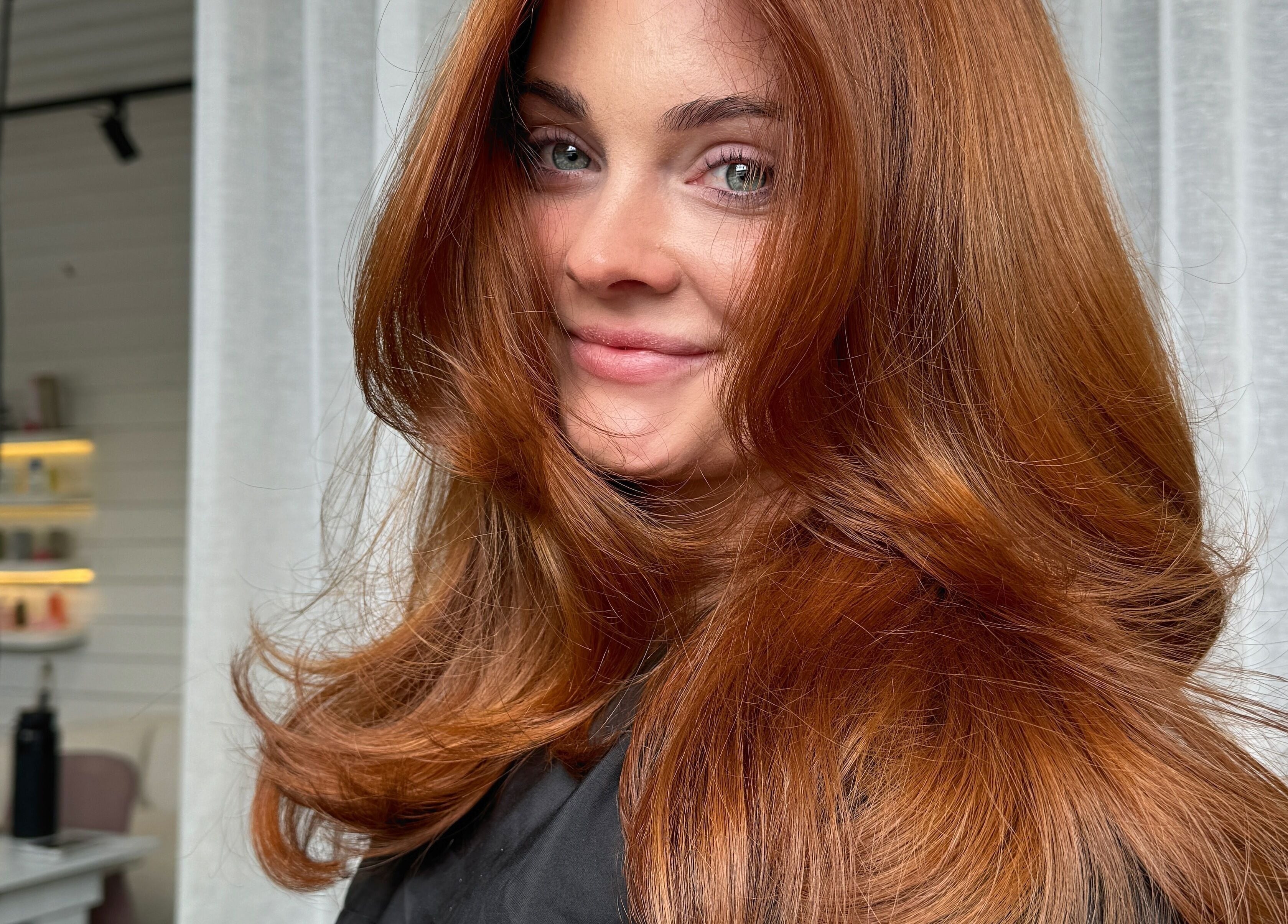 Woman with vibrant auburn hair at Rinsd Hair, Palm Beach, Queensland, AU, showcasing expert styling and color.