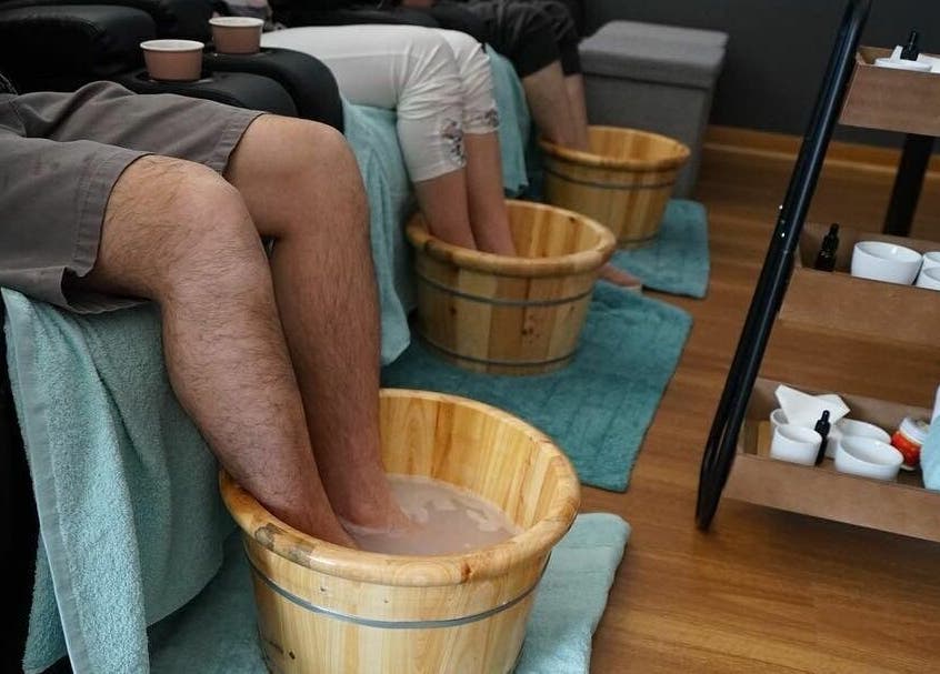 Patrons enjoy a soothing foot soak at Oceanic Spa Moonah in Moonah, Tasmania, AU with wooden tubs and cozy towels.