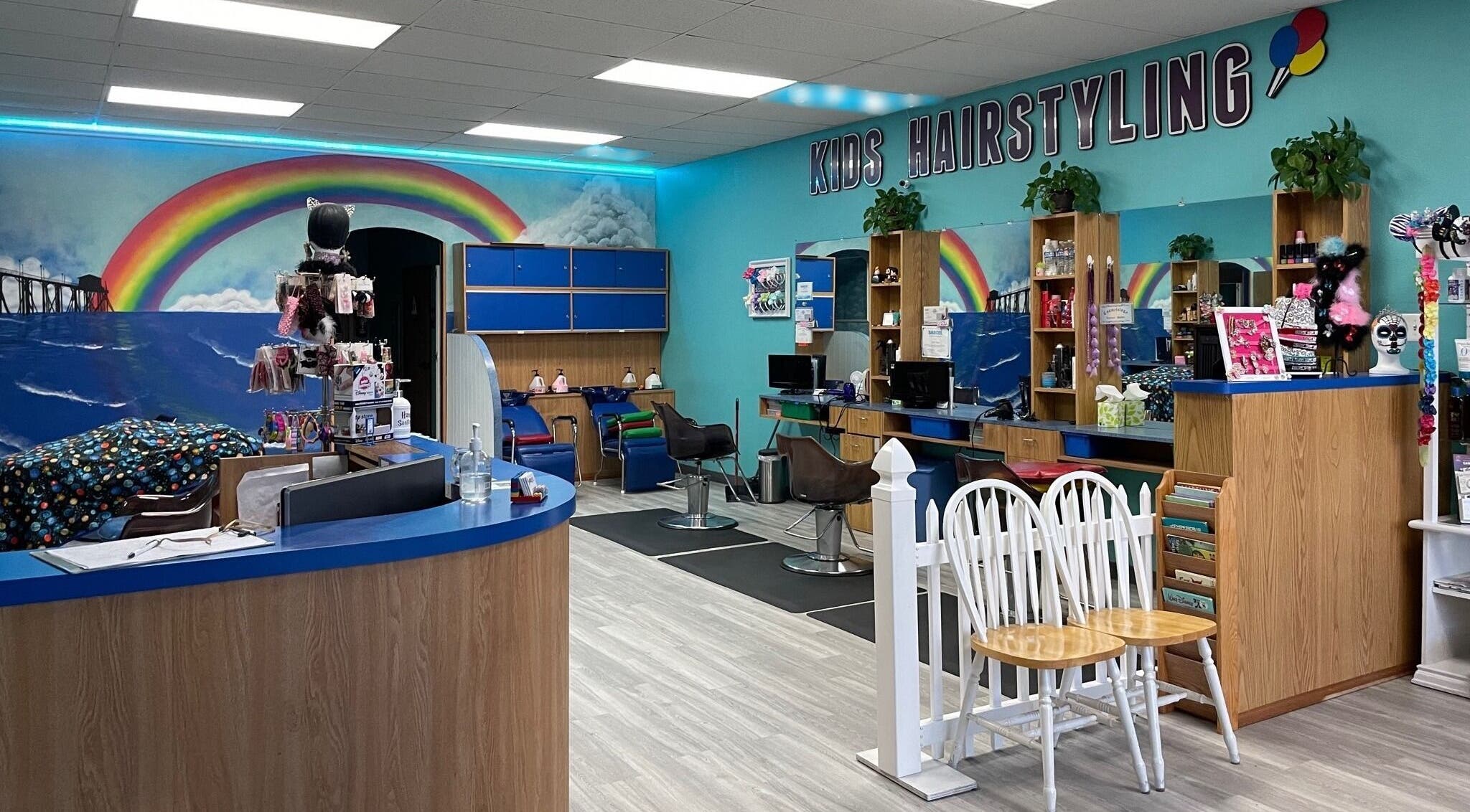Bright interior of Rainbow Kids Hairstyling HB in Huntington Beach, California, US with colorful decor and kids' chairs.