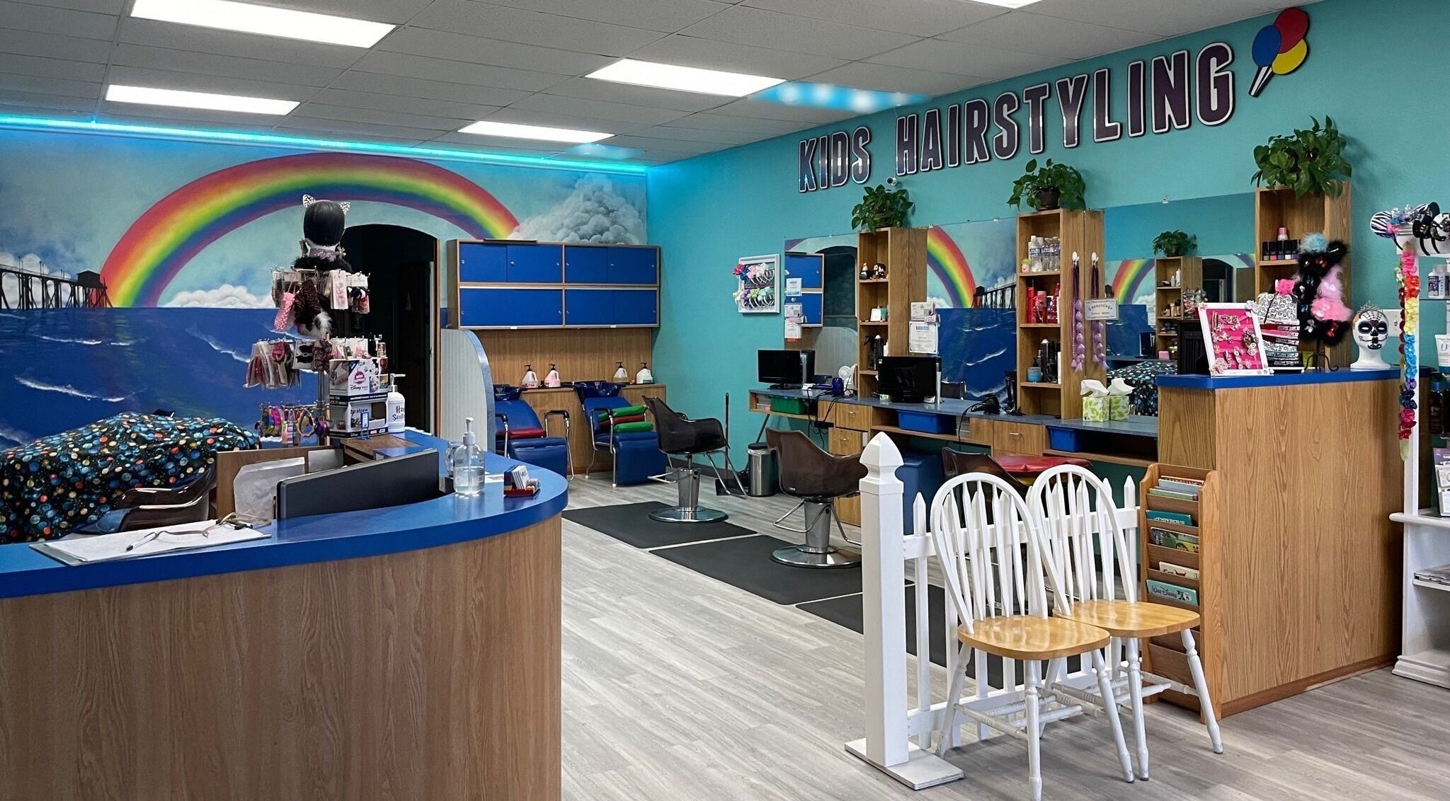 Bright interior of Rainbow Kids Hairstyling HB in Huntington Beach, California, US with colorful decor and kids' chairs.