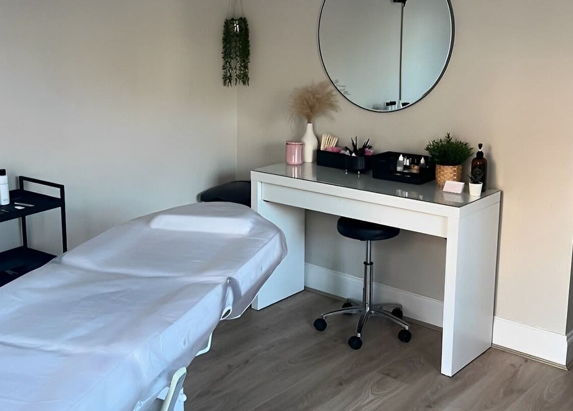 Treatment room at Victoria Alice Brows, Newbury, England, GB. Features massage table and vanity with round mirror.