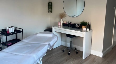 Treatment room at Victoria Alice Brows, Newbury, England, GB. Features massage table and vanity with round mirror.