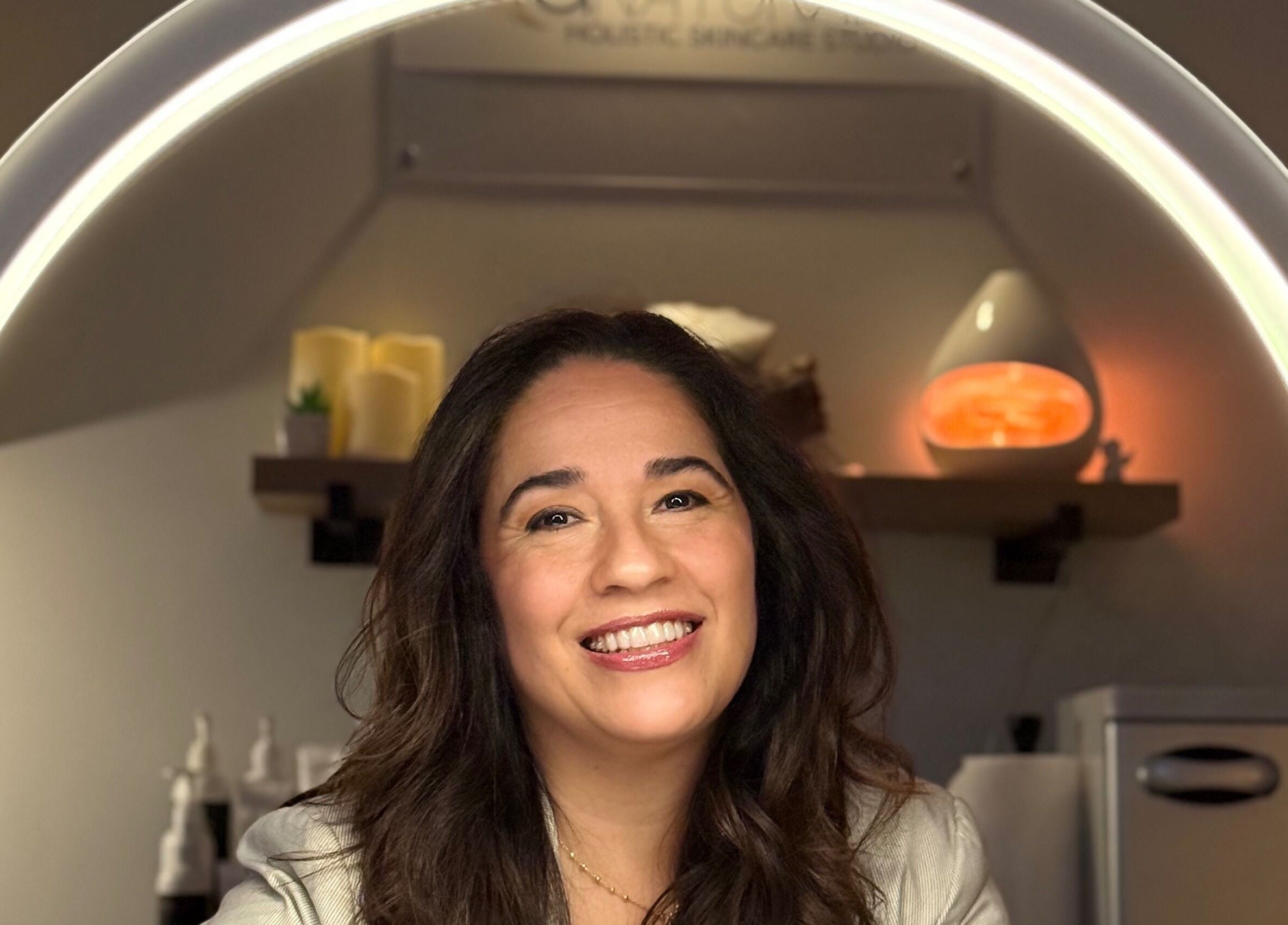 Woman smiling under skincare light at ANATURALE HOLISTIC SKINCARE STUDIO, Henrico, Virginia, US.