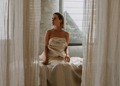 Woman in a serene setting at UMICA, Byron Bay, New South Wales, AU, surrounded by soft curtains.