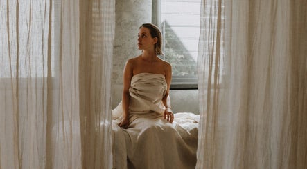 Woman in a serene setting at UMICA, Byron Bay, New South Wales, AU, surrounded by soft curtains.