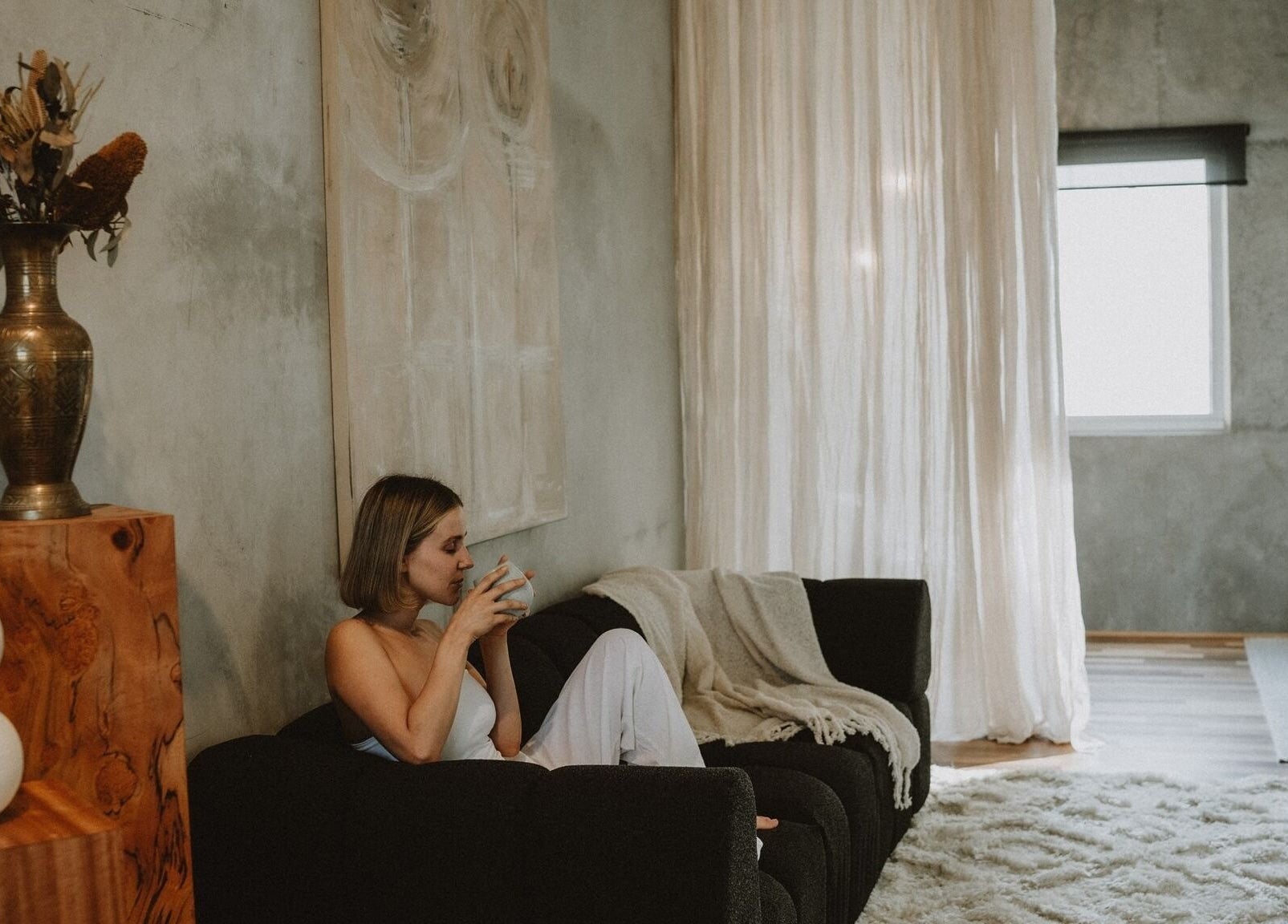 Woman relaxing on a sofa with a warm beverage, UMICA, Byron Bay, New South Wales, AU.
