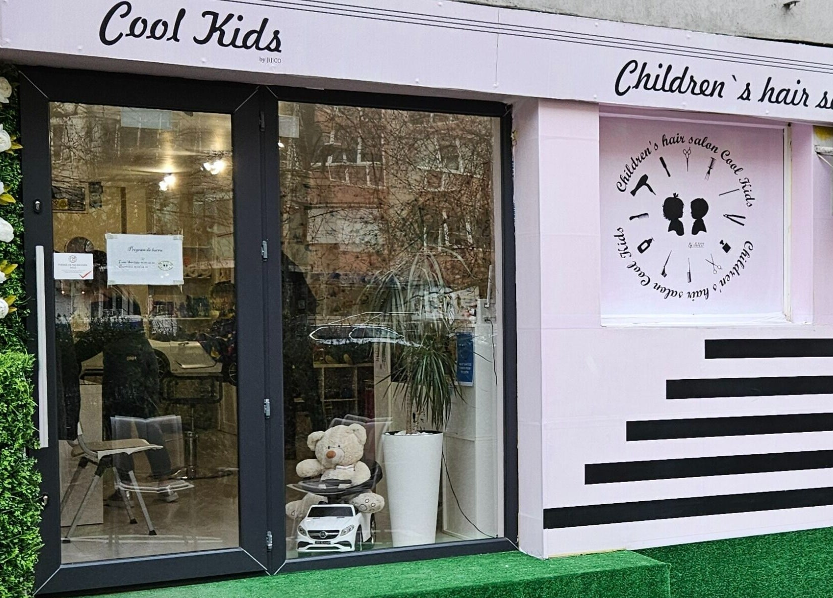 Intrarea modernă a salonului Cool Kids din București, București, RO, cu exteriorul decorat cu flori albe.