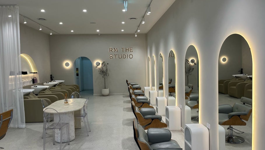 Elegant interior of RM The Studio in Melbourne, Victoria, AU, showcasing modern salon chairs and arched mirrors.
