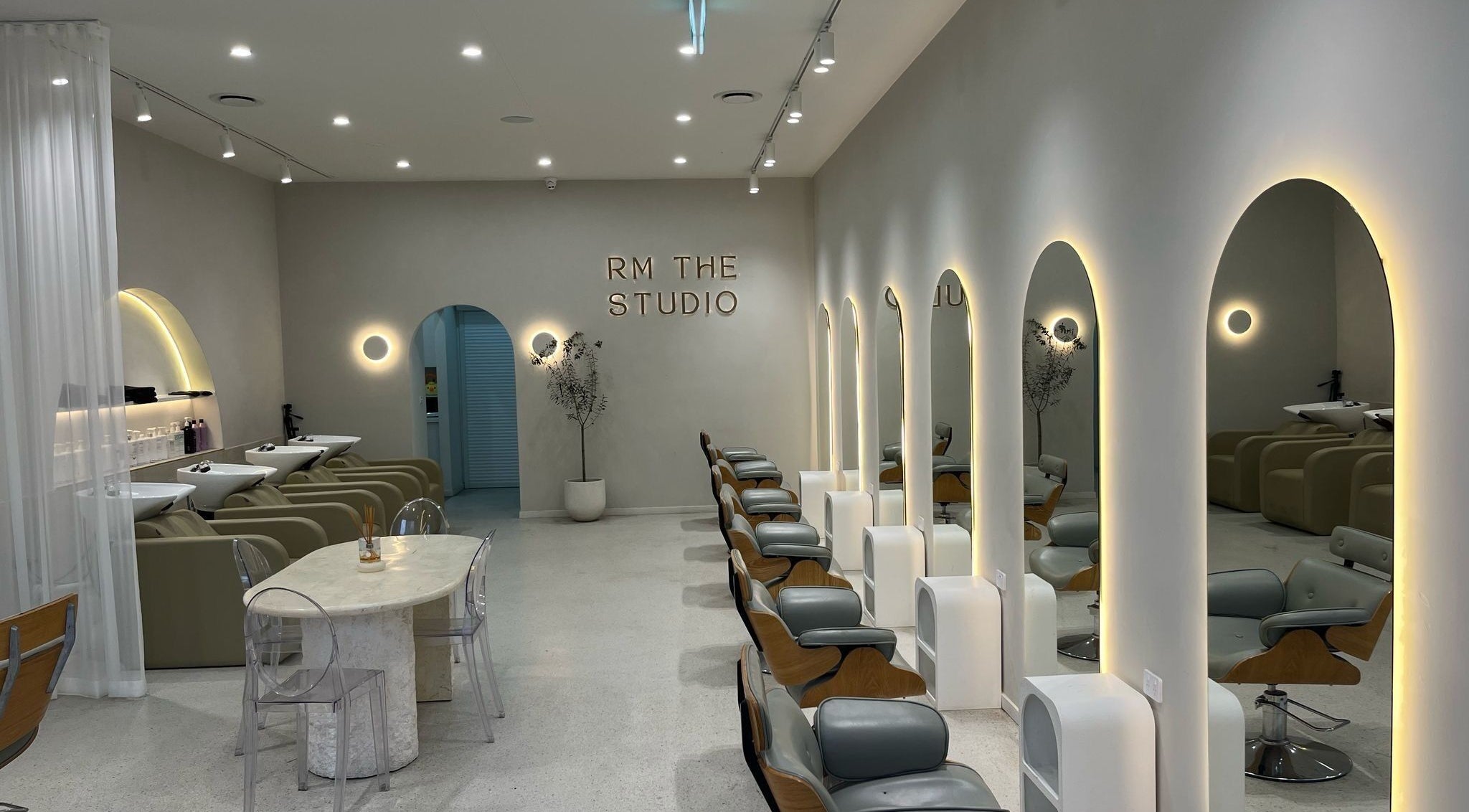 Elegant interior of RM The Studio in Melbourne, Victoria, AU, showcasing modern salon chairs and arched mirrors.