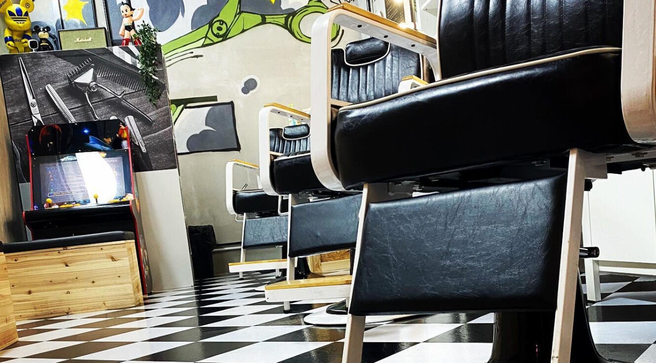 Stylish interior of BT Barbershop The Sphere, Kuala Lumpur, showcasing vintage arcade and art decor.