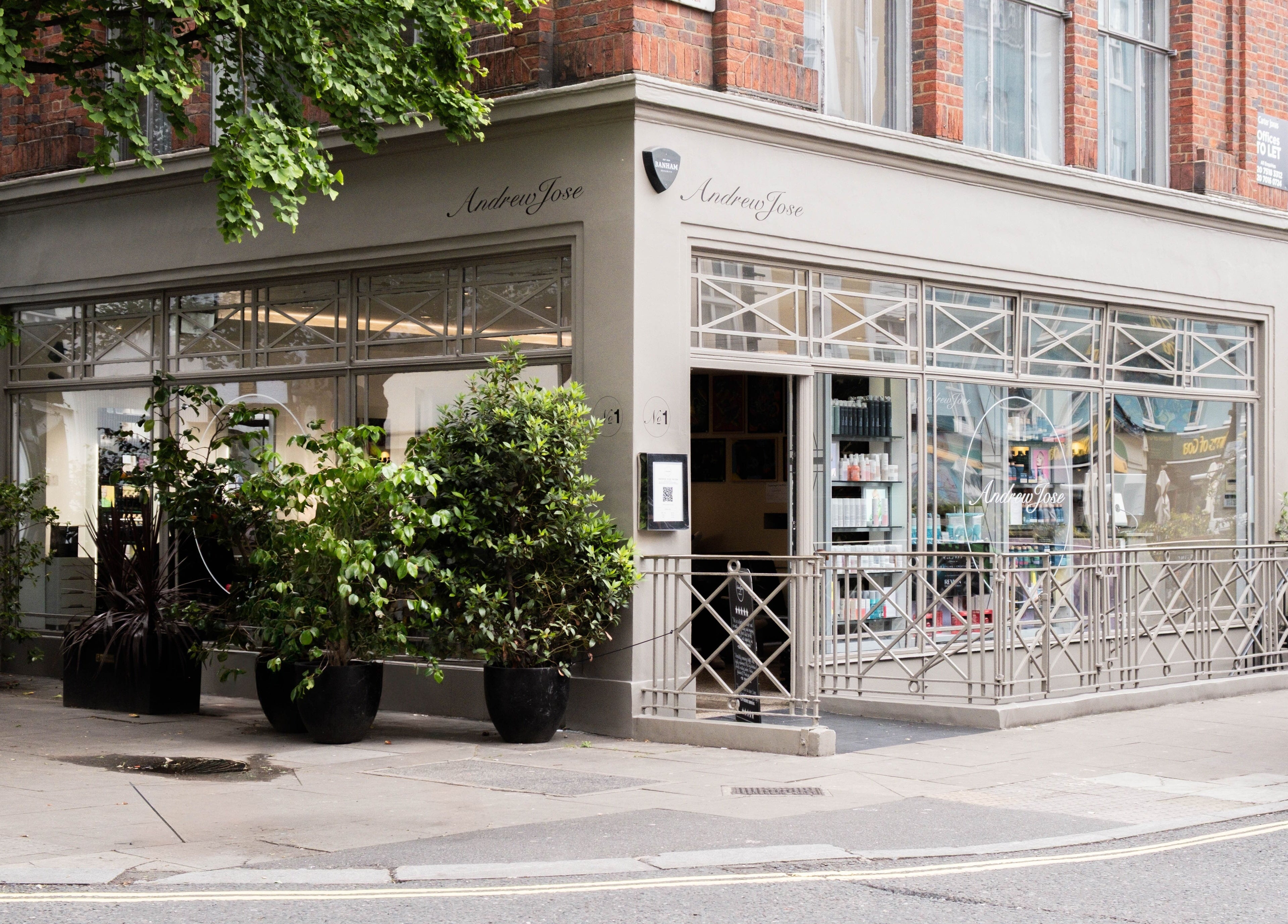 Exterior of Andrew Jose beauty salon in London, England, GB with modern window displays and greenery.